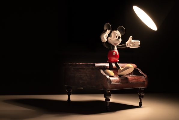 Figur Mickey Mouse tanzt auf einem Klavier und dient zur Inspiration um als Autor Roman Figuren entwickeln zu können